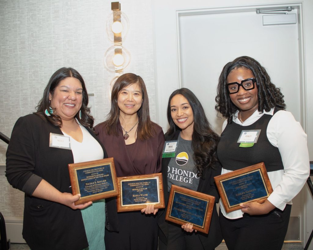 Dr. Xueli Wang smiles in a group photo with her former advisees Dr. Nicole Soulier and Dr. Ashley Gaskew and current PhD advisee Nicole Contreras-García at the Council for the Study of Community Colleges (CSCC) 2025 Annual Conference. Each person is holding a plaque for an award they received at the conference: (left to right) Nicole Soulier - 2025 CSCC Richard M. Romano Dissertation of the Year Award; Xueli Wang - 2025 CSCC Senior Scholar Award; Nicole Contreras García - 2025 CSCC Outstanding Doctoral Student Award; Ashley Gaskew - 2025 CSCC Research Grant.