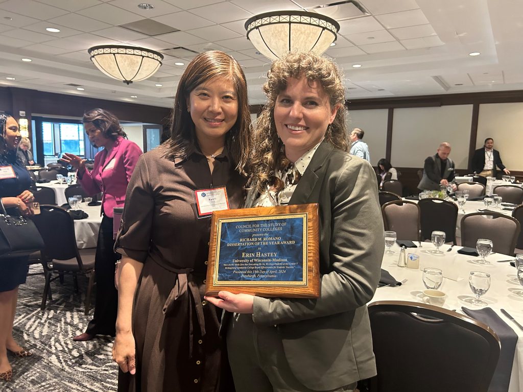 Dr. Erin Hastey (Right) with her doctoral advisor Dr. Xueli Wang (Left) after receiving her "Dissertation of the Year Award" at the Council for the Study of Community Colleges (CSCC) 2024 Annual Conference. The two are smiling at the camera in a conference dining room.