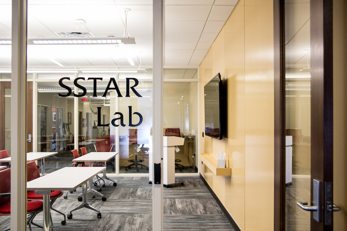 A classroom behind a glass wall that has text saying "SSTAR Lab."