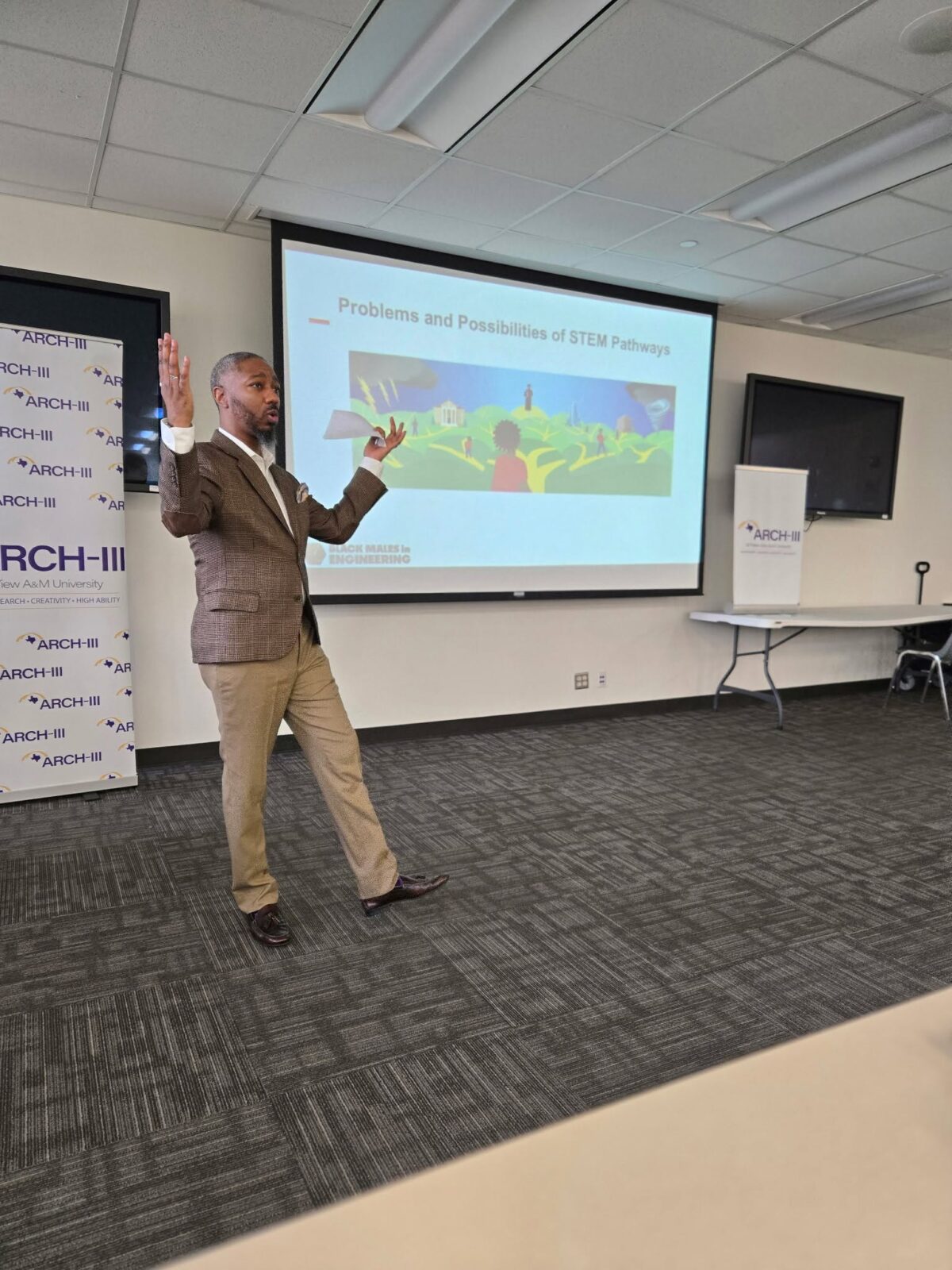 Dr. Brian A. Burt standing in front of a projection screen and presenting to a room of off-camera listeners.
