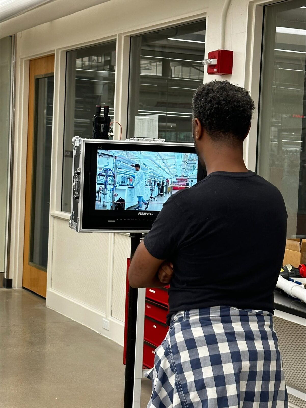 Dr. Brian A. Burt standing behind a video monitor reviewing a filming take from a video project.