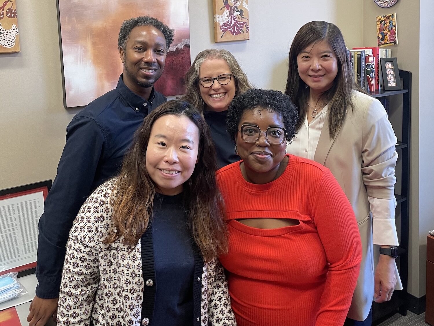 A group picture of Higher Education professors smiling at the camera in an office. From left to right, the picture features (front row) Dr. Jing Yu, Dr. Aireale Rodgers, (back row) Dr. Brian Burt, Dr. Rachelle Winkle-Wagner, and Dr. Xueli Wang