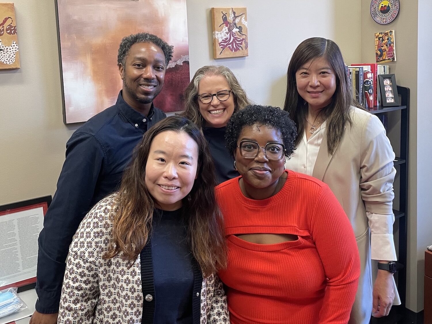 A group picture of Higher Education professors smiling at the camera in an office. From left to right, the picture features (front row) Dr. Jing Yu, Dr. Aireale Rodgers, (back row) Dr. Brian Burt, Dr. Rachelle Winkle-Wagner, and Dr. Xueli Wang