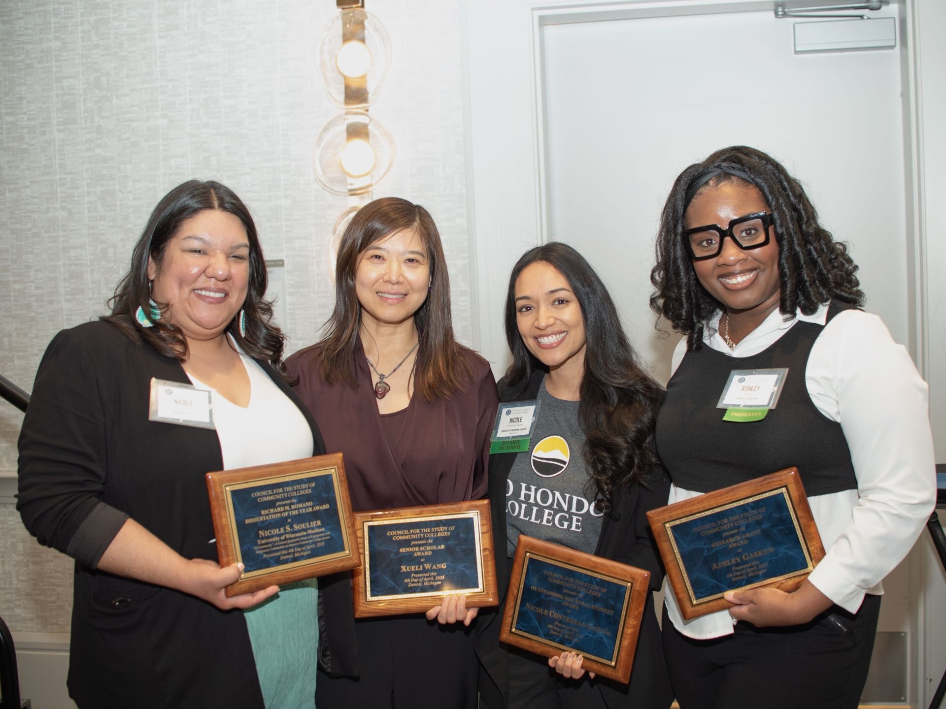 Dr. Xueli Wang smiles in a group photo with her former advisees Dr. Nicole Soulier and Dr. Ashley Gaskew and current PhD advisee Nicole Contreras-García at the Council for the Study of Community Colleges (CSCC) 2025 Annual Conference. Each person is holding a plaque for an award they received at the conference: (left to right) Nicole Soulier - 2025 CSCC Richard M. Romano Dissertation of the Year Award; Xueli Wang - 2025 CSCC Senior Scholar Award; Nicole Contreras García - 2025 CSCC Outstanding Doctoral Student Award; Ashley Gaskew - 2025 CSCC Research Grant.